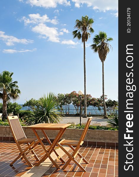 Table with two chairs and two tool palms with beautiful sky in the background. Table with two chairs and two tool palms with beautiful sky in the background