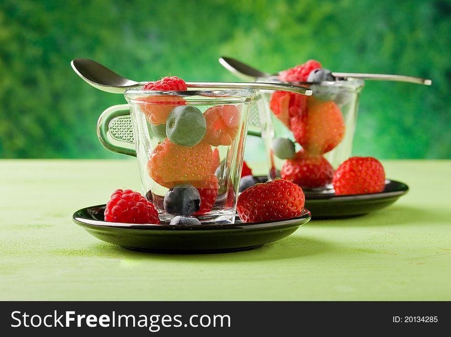 Photo of delicious berries inside a glass cup with green background