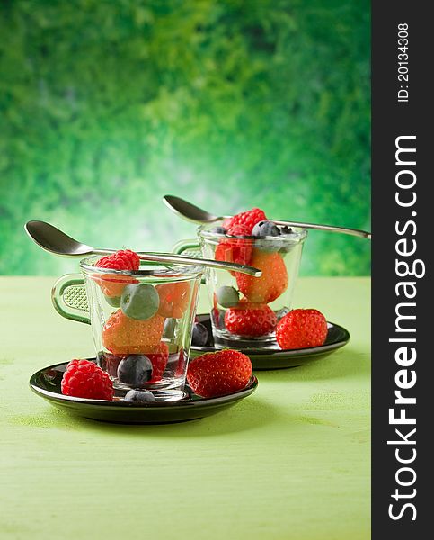 Photo of delicious berries inside a glass cup with green background