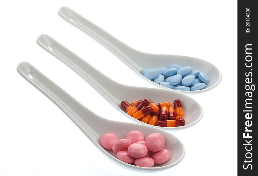 Three ceramic spoons with colorful pills, isolated. Three ceramic spoons with colorful pills, isolated