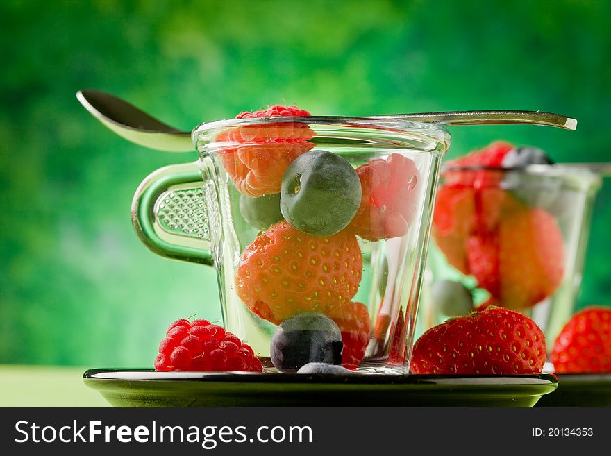 Photo of delicious berries inside a glass cup with green background