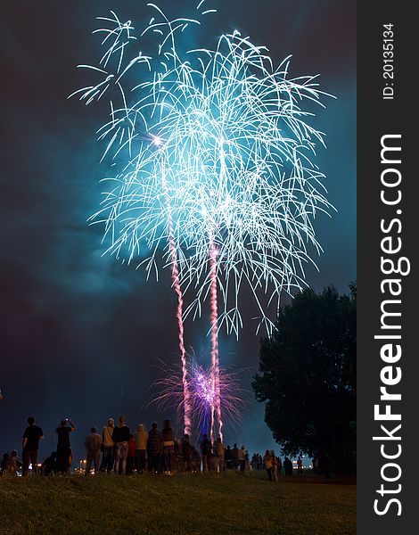 People watching beautiful blue fireworks on the hill