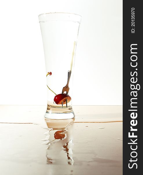 Cherry and little fork in glass full of water. Cherry and little fork in glass full of water.