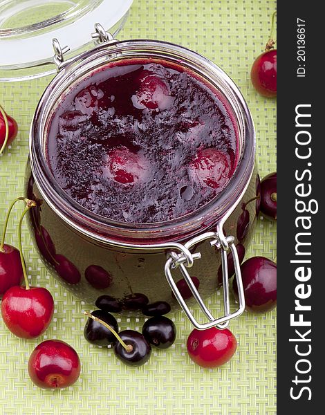 Studio-shot of homemade cherry jam in a glass jar.