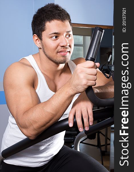 Sportsman is exercising in gym room. Sportsman is exercising in gym room