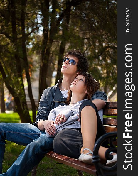 Attractive couple sitting on bench in the park and looking up. Attractive couple sitting on bench in the park and looking up