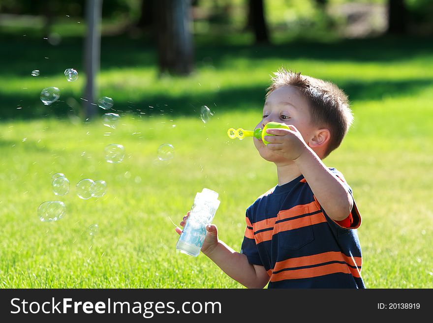 Little boy blowing soap bubbles at the park. Little boy blowing soap bubbles at the park