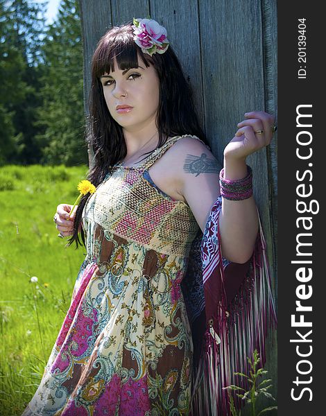 Gypsy woman standing in a country scene holding a yellow dandelion. Gypsy woman standing in a country scene holding a yellow dandelion.