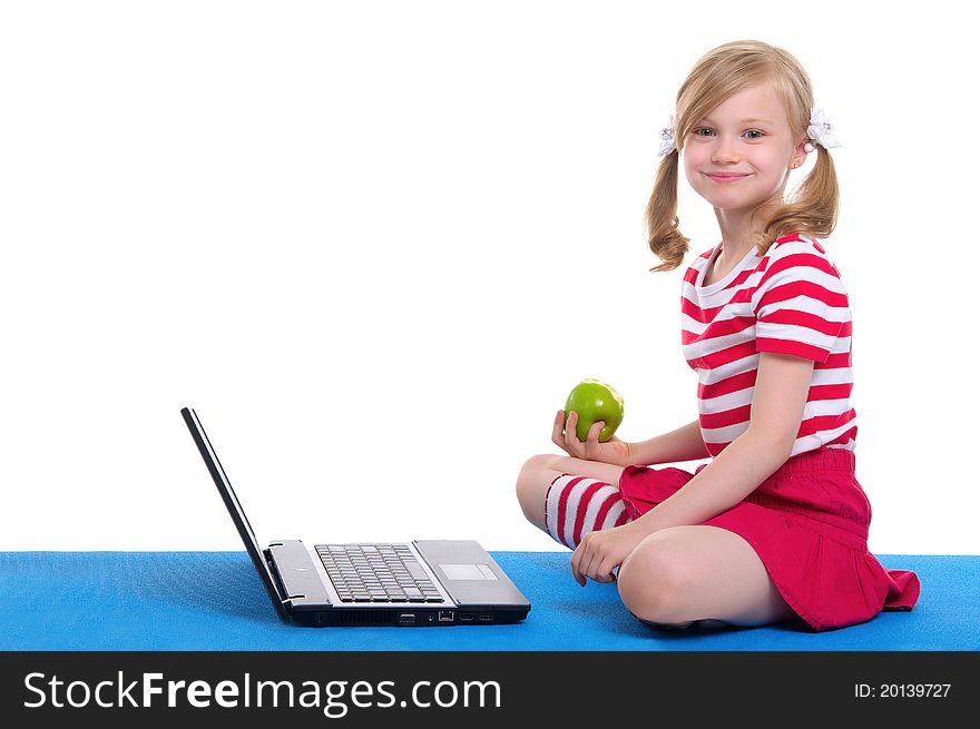 Girl with an apple and laptop sitting on blue rug