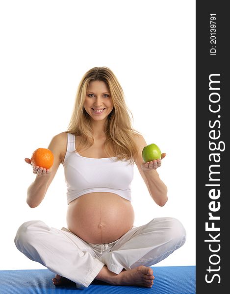 Pregnant woman practicing yoga and keeps fruit