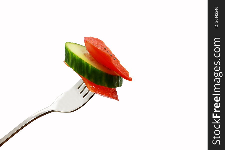 Slices of red pepper and cucumber on the fork isolated. Slices of red pepper and cucumber on the fork isolated