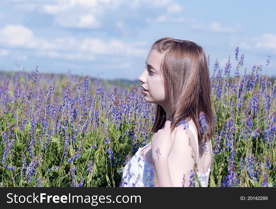 Young girl looking at the side in a meadow among flowers. Young girl looking at the side in a meadow among flowers