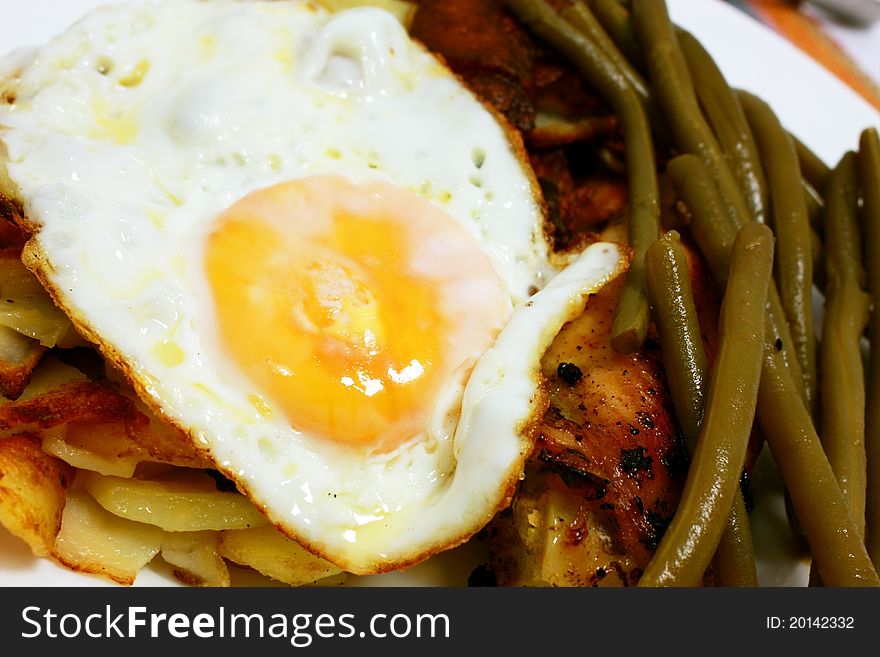 Scrambled egg, bean pods and fried potatoes close up