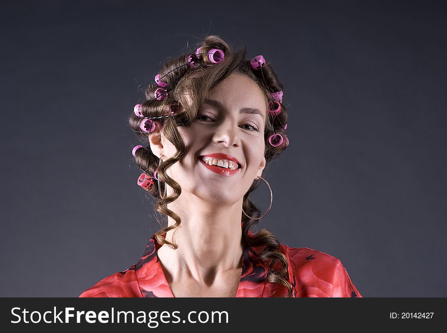 Portrait of a young beautiful woman with bigoudi on the hair on a gray background closeup. Portrait of a young beautiful woman with bigoudi on the hair on a gray background closeup