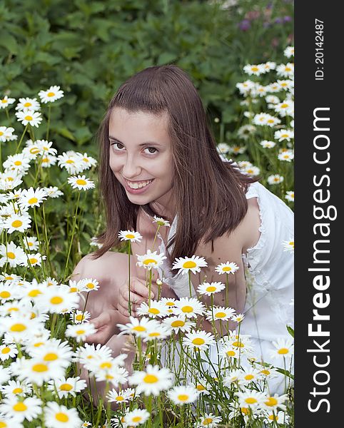 Portrait of smiling young girl sitting among daises. Portrait of smiling young girl sitting among daises