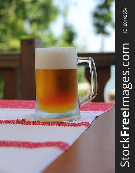 Glass pint of beer on the table with a large foam misted with cold