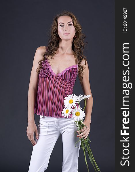 Portrait of a  young beautiful woman with camomile on a gray background closeup. Portrait of a  young beautiful woman with camomile on a gray background closeup