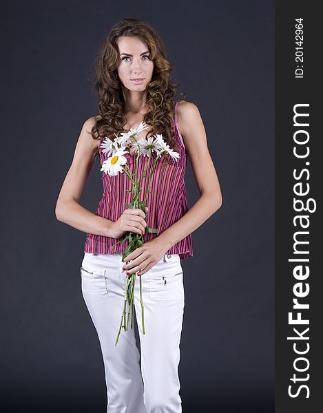 Portrait of a young beautiful woman with camomile on a gray background closeup. Portrait of a young beautiful woman with camomile on a gray background closeup