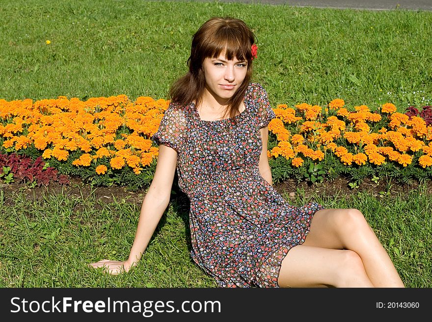 Beautiful girl sitting on meadow with flowers