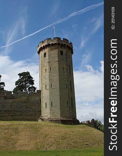 Stone built historical tower with slits, windows and ramparts on a grass mound with a blue sky in the background. Stone built historical tower with slits, windows and ramparts on a grass mound with a blue sky in the background.