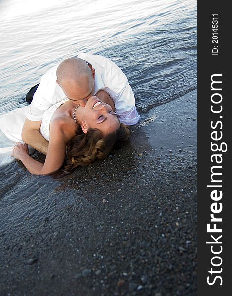 A groom kissing brides neck on beach. A groom kissing brides neck on beach