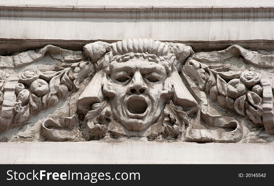 Bas-relief man's face on the wall of city street