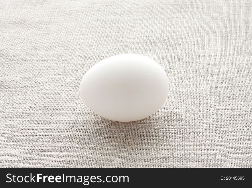 Fresh hen's egg against the background of natural fabric. Fresh hen's egg against the background of natural fabric