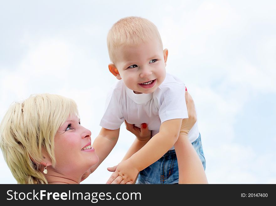 Portrait of mother holding her little baby outdoors in the summer