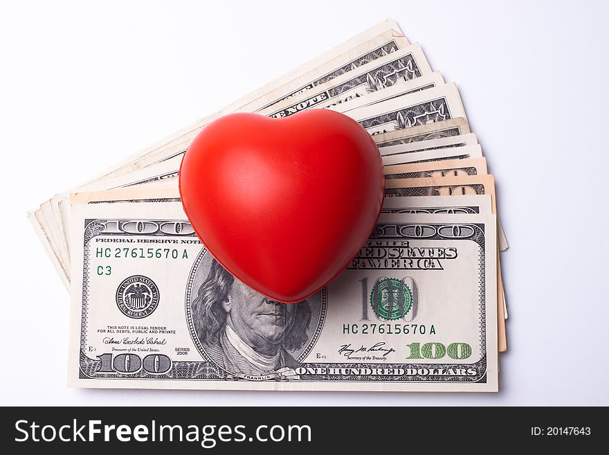 Red heart on top of dollar bank notes isolated on white. Red heart on top of dollar bank notes isolated on white