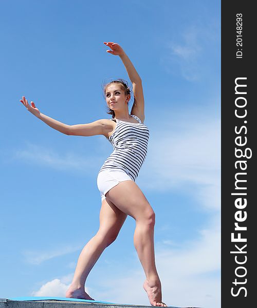 Portrait of a young woman doing exercises against blue sky