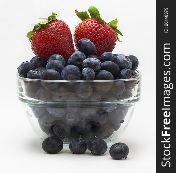 A cup of blueberries and strawberries on a white background