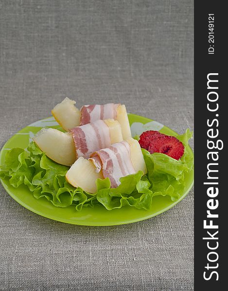 Melon with Parma ham on a green plate