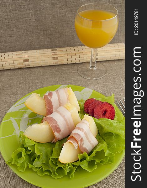 Melon with Parma ham on a green plate