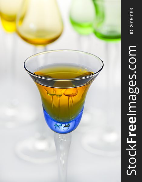 A colorful glass of liqueur with focus in the foreground and shallow depth of field, reflects glasses in the background. A colorful glass of liqueur with focus in the foreground and shallow depth of field, reflects glasses in the background