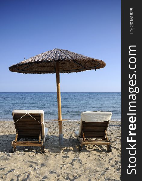 Beach umbrella and two chairs over the sea