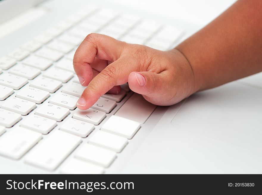 The photo of little finger of an asian toddler typing on laptop's keyboard. The photo of little finger of an asian toddler typing on laptop's keyboard.