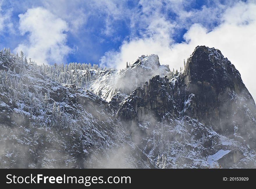 Clouds clearing on Cathedral Rocks with a fresh coating on the ridge trees in Yosemite National Park, California. Clouds clearing on Cathedral Rocks with a fresh coating on the ridge trees in Yosemite National Park, California