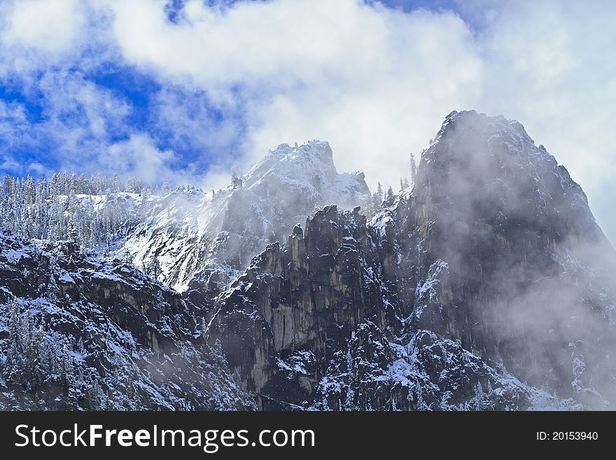 Clouds clearing on Cathedral Rocks with a fresh coating on snow on the ridge trees in Yosemite National Park, California. Clouds clearing on Cathedral Rocks with a fresh coating on snow on the ridge trees in Yosemite National Park, California