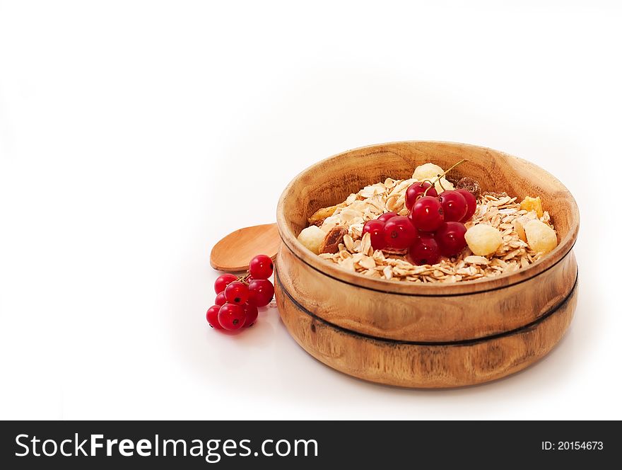 Cereals with red currants in wood bowl over white