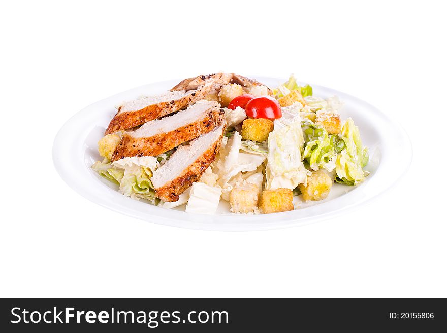 Caesar salad with chicken on a plate. On a white background.