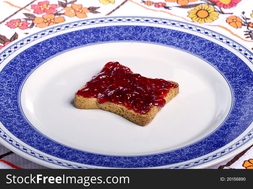 Close view of a toasted bread with berry jam spread   on a white background. Close view of a toasted bread with berry jam spread   on a white background.