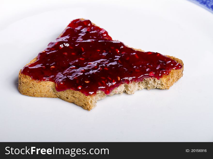 Close view of a toasted bread with berry jam spread on a white background. Close view of a toasted bread with berry jam spread on a white background.