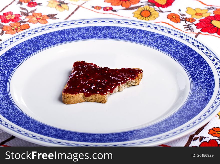 Close view of a toasted bread with berry jam spread on a white background. Close view of a toasted bread with berry jam spread on a white background.