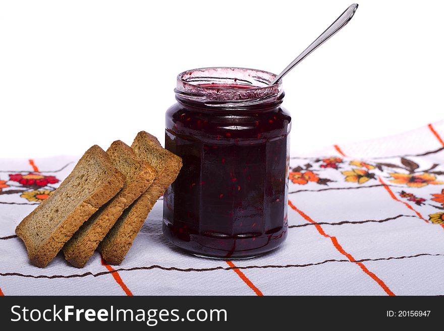 Close view of a toasted bread with berry jam jar isolated on a white background. Close view of a toasted bread with berry jam jar isolated on a white background.