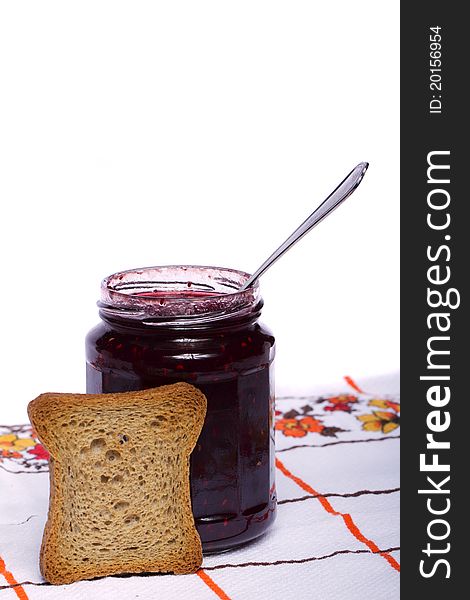 Close view of a toasted bread with berry jam jar isolated on a white background. Close view of a toasted bread with berry jam jar isolated on a white background.