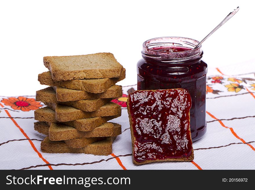 Close view of a toasted bread with berry jam jar isolated on a white background. Close view of a toasted bread with berry jam jar isolated on a white background.