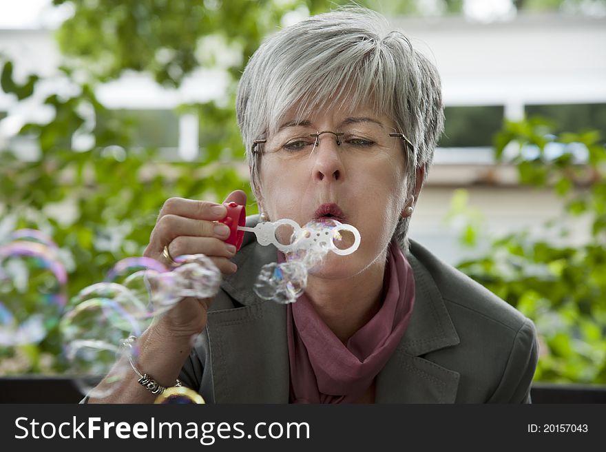 Woman, 50 +, blowing soap bubbles. Woman, 50 +, blowing soap bubbles