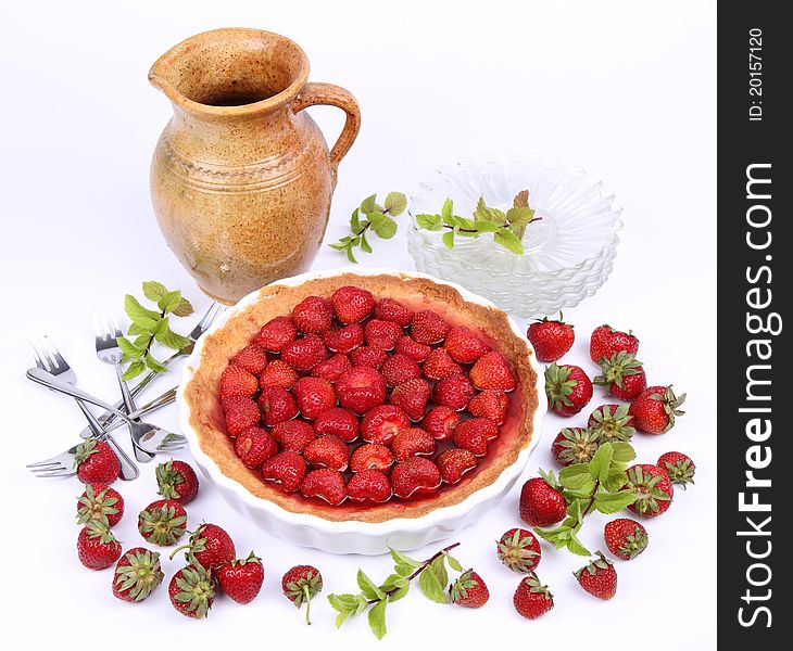 Strawberry Tart, plates, a pot, forks, strawberries and mint twigs on a white background