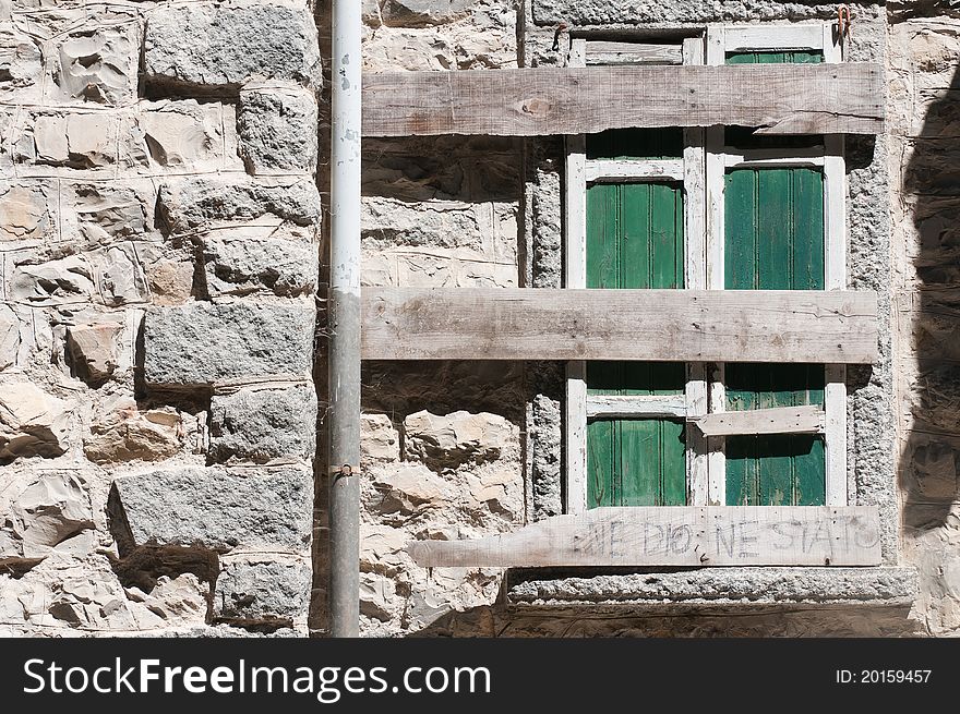 A barred wooden window on the wall of a tumbledown house. A barred wooden window on the wall of a tumbledown house.