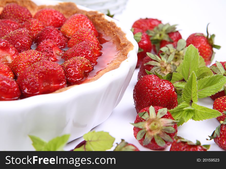 Strawberry Tart decorated with strawberries and mint twigs on a white background